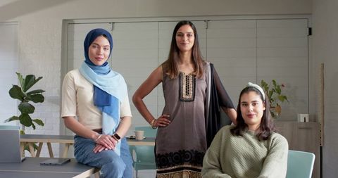 Multicultural women posing in office collaboration space wearing headscarves and casual attire