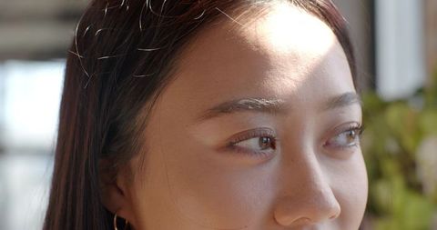 Woman Gazing Through Sunlit Window with Serene Expression