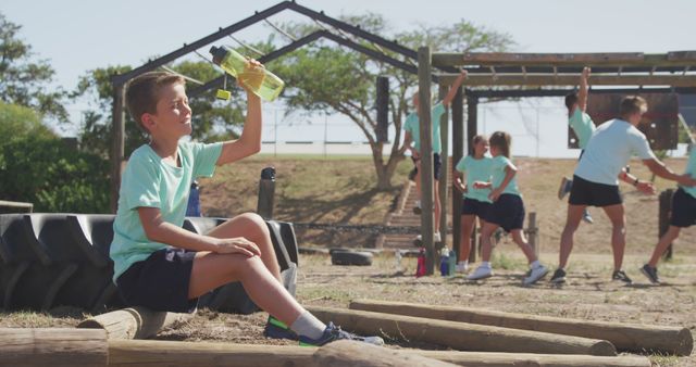 Boy Taking Break on Outdoor Obstacle Course with Friends - Download Free Stock Images Pikwizard.com