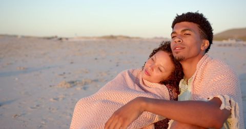 Romantic Couple Wrapped in Blanket on Beach at Sunset