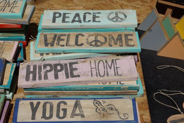 Collection of colorful wooden signboards featuring phrases like Peace, Welcome, Hippie Home, and Yoga. These rustic, handmade items are perfect for adding a positive and bohemian touch to any home or garden. Ideal for use in marketing materials aimed at peaceful living, yoga, and bohemian decor.