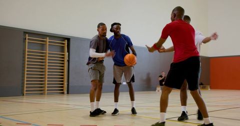 Indoor basketball game with players dribbling, defending, and practicing teamwork on court