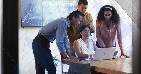 Diverse team collaborating around laptop during product launch meeting in modern office