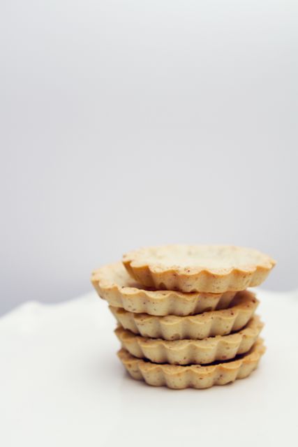 Image shows a stack of homemade, organic mini pie crusts against a plain white background. Perfect for use in culinary blogs, recipe books, advertisements for baking ingredients, or online food stores highlighting organic and homemade products.
