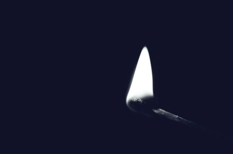 Single Burning Matchstick in Dark Background