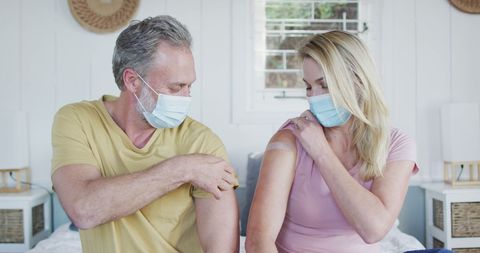 Happy Mature Couple Showing Vaccinated Arms at Home