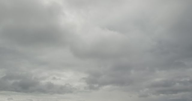 Low angle view of white and grey clouds moving across blue sky on a windy day and covering it in fast motion