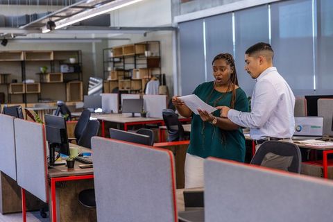 Diverse coworkers discussing report in open-plan office