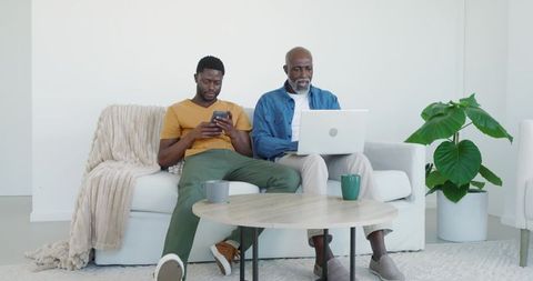 African american father and son bonding at home with gadgets