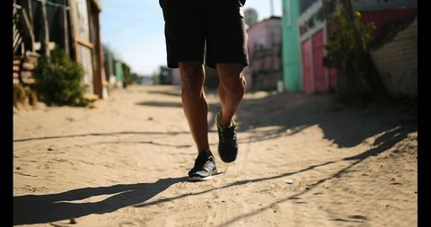 Young man jogging on sandy path during daytime for fitness