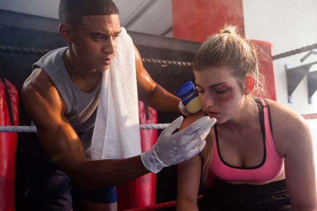 Trainer applying cream on woman face in boxing ring