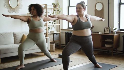 Plus-Size Friends Practicing Warrior II Yoga at Home Embracing Body-Positive Cozy Wellness