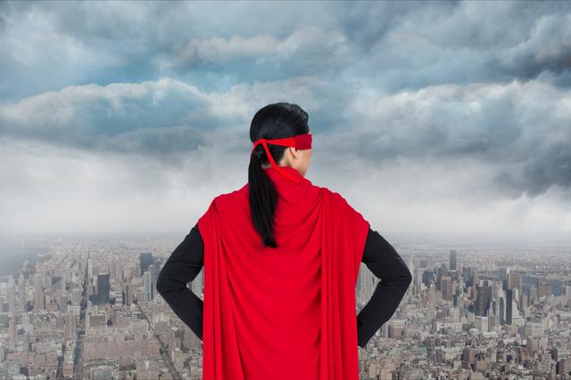 This image depicts a woman in a red superhero costume standing on a high point, overlooking a city skyline. The sky is filled with clouds, giving a dramatic and empowering feel. This image is perfect for articles, advertisements, and campaigns focusing on empowerment, leadership, and confidence.
