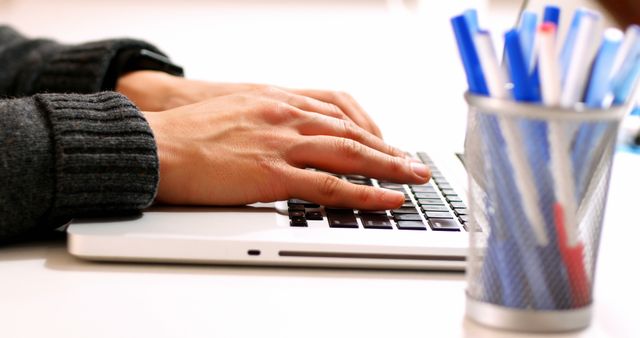 Person typing on laptop keyboard with pen holder on desk - Download Free Stock Images Pikwizard.com