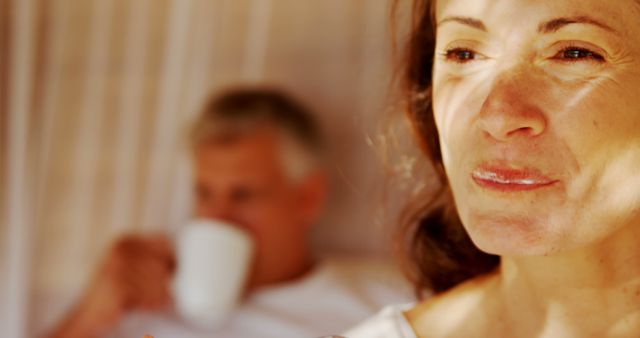 Middle-aged woman reflecting with man drinking coffee in background - Download Free Stock Images Pikwizard.com