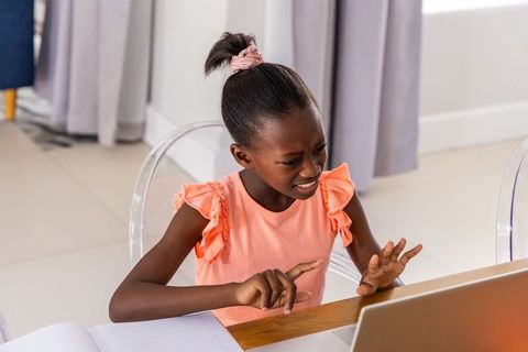 African american girl frustrated at laptop during remote learning at home