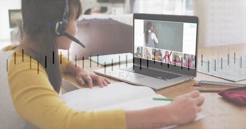 Child wearing headset taking notes during virtual classroom with teacher writing on chalkboard