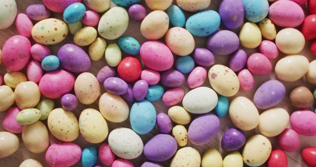 Assorted colorful candy Easter eggs scattered on a wooden surface. Ideal for use in holiday-themed promotions, greeting cards, or advertisements. Perfect for illustrating springtime celebrations, Easter events, or festive decorations.