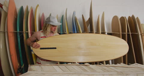 Surfboard Maker Examining Handcrafted Board in Workshop