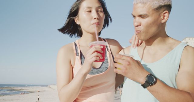 Young couple enjoying refreshing beverages together near beach. Ideal for summer vacation, relaxation, leisure time, and lifestyle promotions. Perfect for travel agencies, beverage brands, and beach resort advertisements.