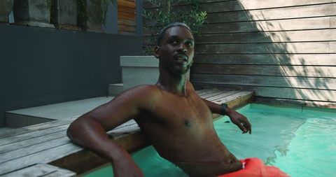 African American Man Relaxing in Vibrant Backyard Pool