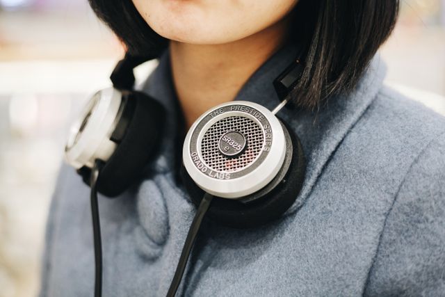 Close-up of person wearing headphones in casual jacket. This is useful for articles on music, technology, fashion, or leisure activities. Perfect for illustrating themes of modern technology, listening habits, and personal style.