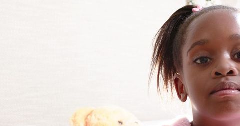 African american child relaxing with teddy bear at home