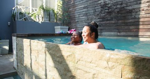 Mother and Daughter Relaxing Together by Pool Under Sunlight