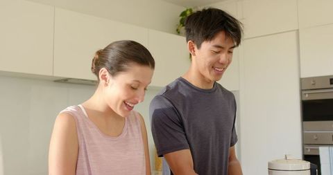 Diverse couple cooking together in bright modern kitchen preparing healthy weeknight meal