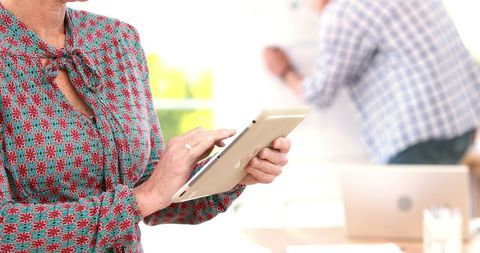 Middle-aged woman using tablet in office environment