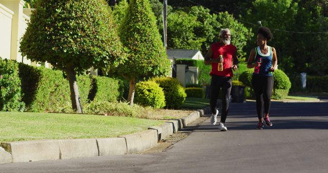 African american senior couple exercising outdoors running in sunny green road - Download Free Stock Photos Pikwizard.com