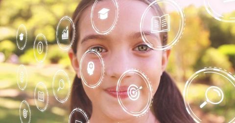 Smiling girl in sunny park surrounded by floating education hud icons for learning