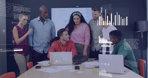 Diverse team collaborating around table with laptops and data charts for strategic planning