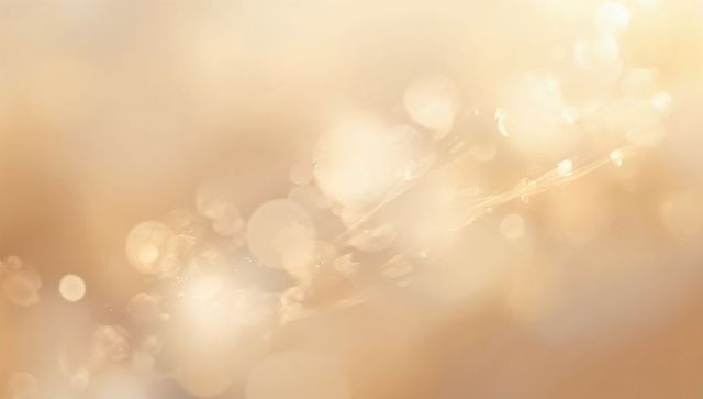 Golden dew on slender grass blade at dawn featuring soft bokeh, warm backlight, macro