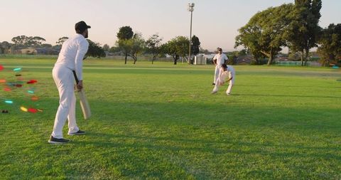 Evening Cricket Batsman Facing Bowler on Sunlit Green Outfield