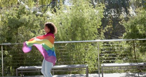 Woman Holding Rainbow Flag Celebrating in Natural Setting