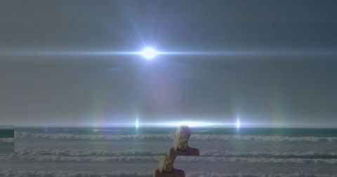 Woman observing mystic ocean scene with rainbow flares
