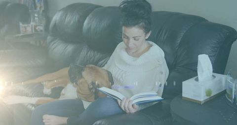 Woman reading with dog on sofa in cozy home living room