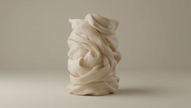 Cream folded sculpture revealing soft layered folds on neutral minimal background