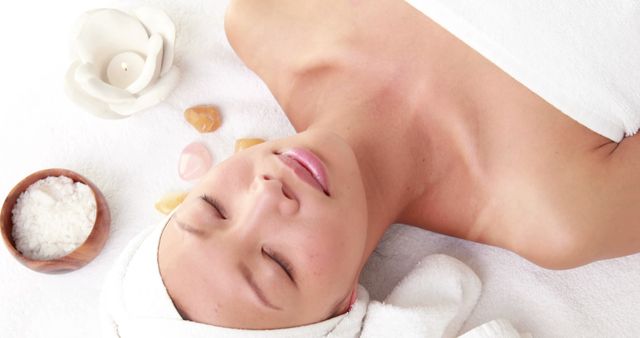 An Asian woman enjoys a relaxing spa treatment, with copy space. Serenity and self-care are emphasized as she lies with stones on her face, embodying tranquility.