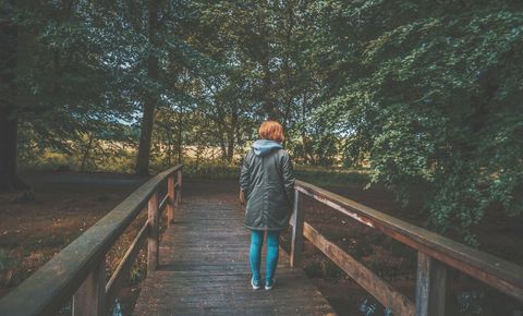 Solitary Figure on Wooden Bridge in Lush Green Forest