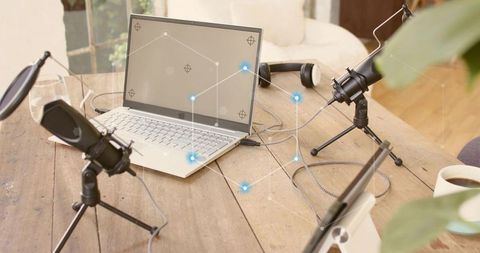 Recording podcast at home with laptop and condenser microphones on rustic wooden table