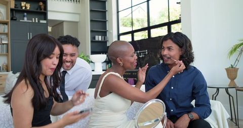 Diverse friends sharing playful makeup moment in modern open-plan living room