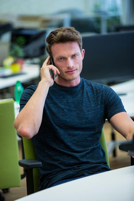Portrait of male business executive talking on mobile phone in office