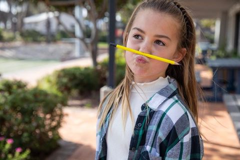 Playful girl balancing pencil outdoors on bright day