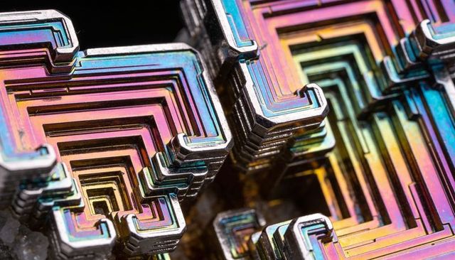 Iridescent bismuth hopper crystals forming geometric stepped terraces macro closeup