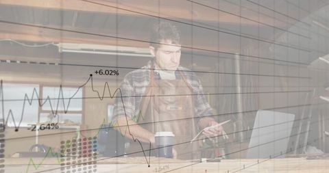 Craftsman integrating technology in carpenter workshop with financial charts