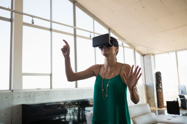 Smiling young businesswoman using virtual reality simulator at office