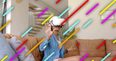 Young woman wearing white vr headset reaching, exploring virtual interface in living room