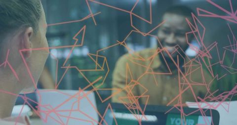 Smiling man leading creative meeting behind glass with pink-orange geometric doodles